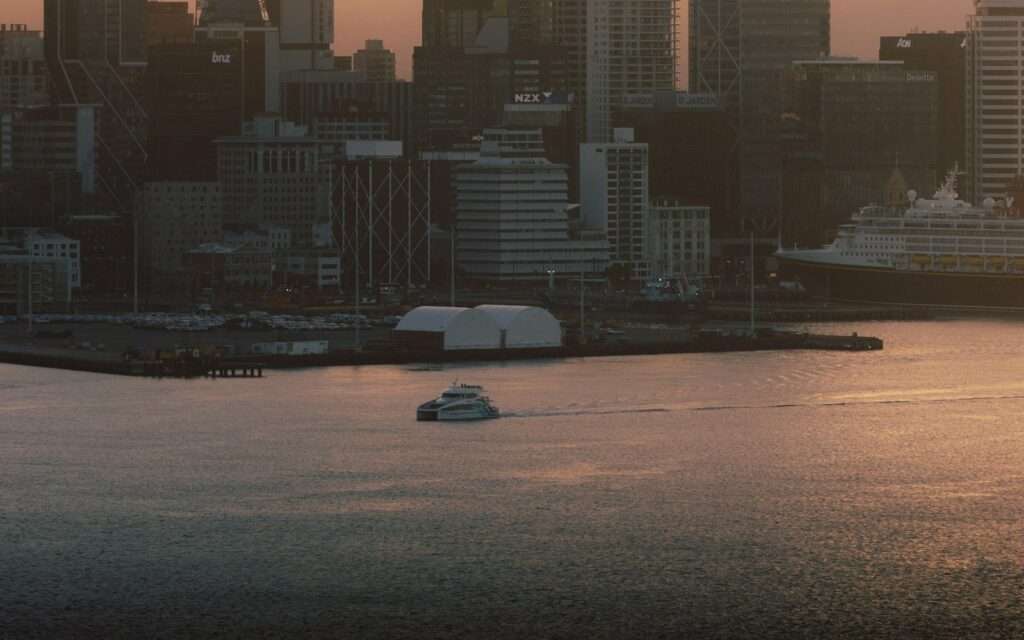 A ferry crossing the Waitemata Harbour in front of the Auckland skyline at dusk