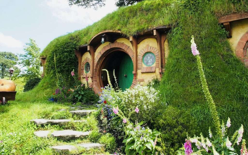 A round green hobbit-hole door in a grassy hillside at the Hobbiton Movie Set