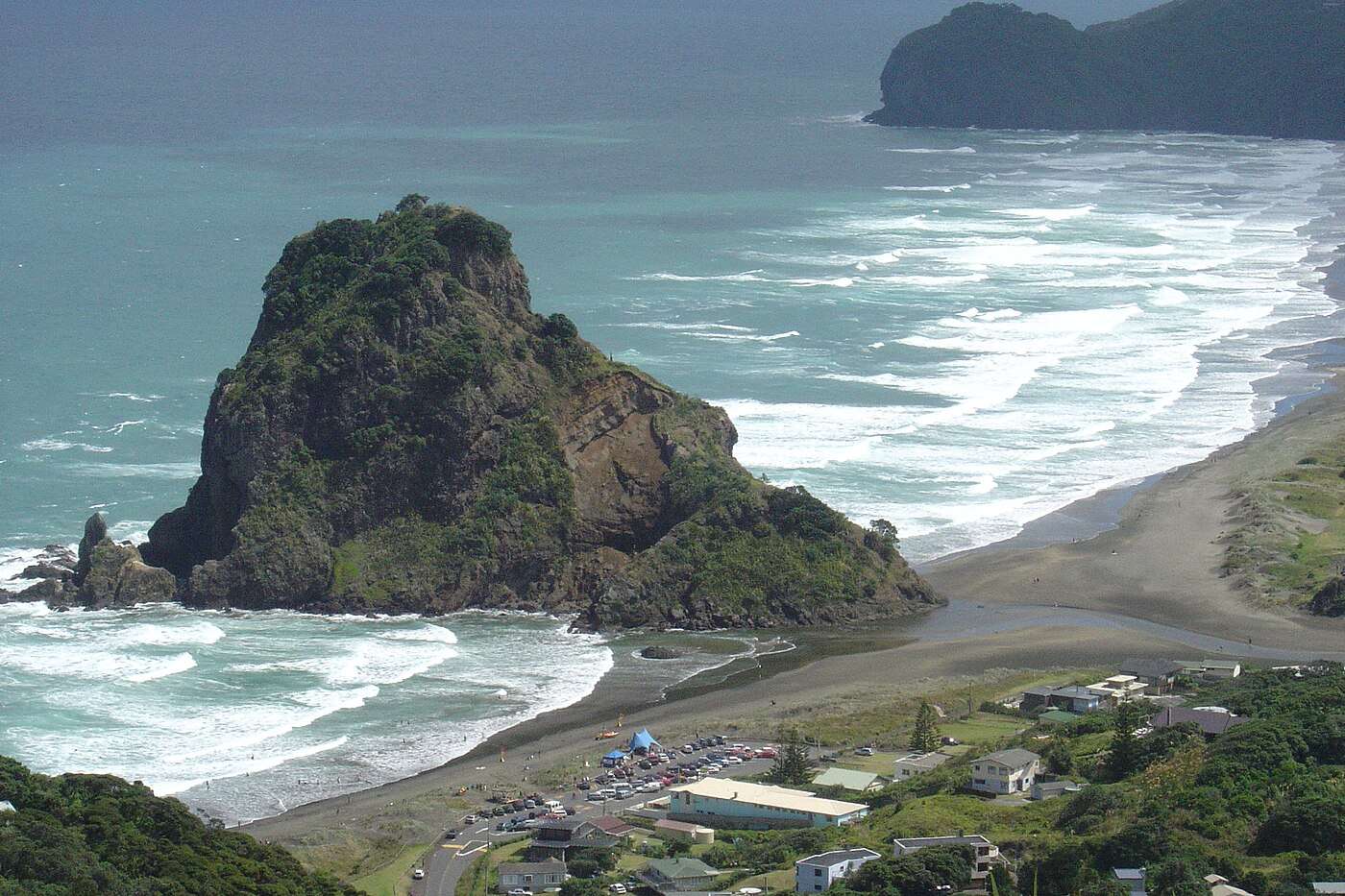 Lion Rock and the black-sand sweep of Piha Beach from the hillside road